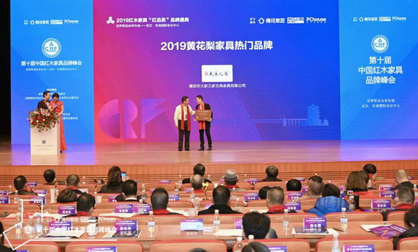 海南花梨文化研究会会长张志扬（左）为“2019黄花梨家具热门品牌”颁奖