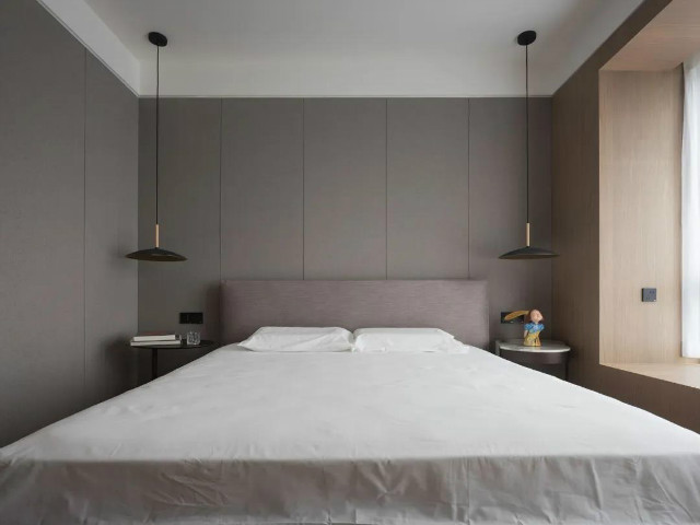 卧室床头墙与侧边墙面都是以灰色的硬包墙面,布置皮质的床铺,整体空间
